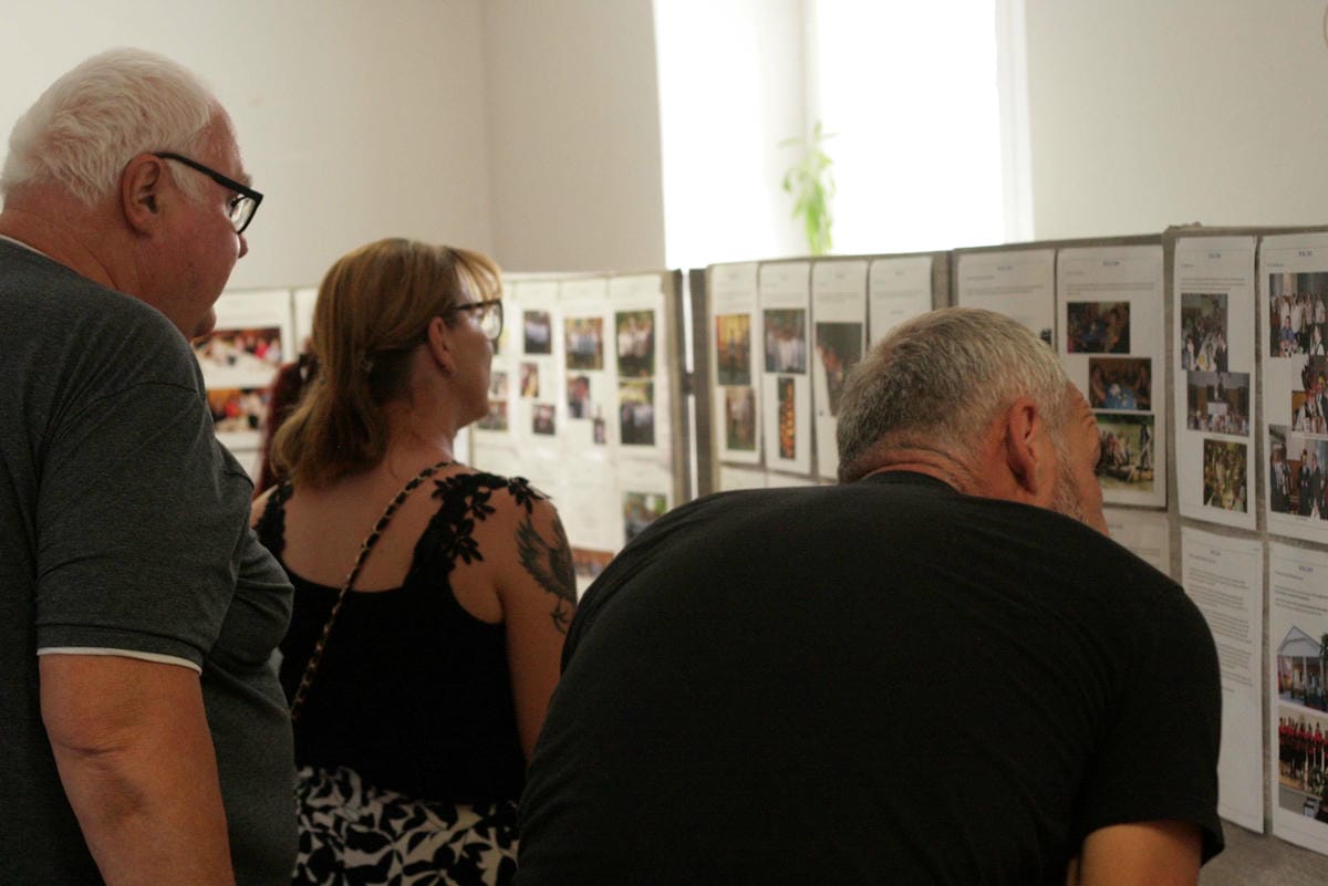 ľudia, ktorí pozerajú na vystavené fotografie